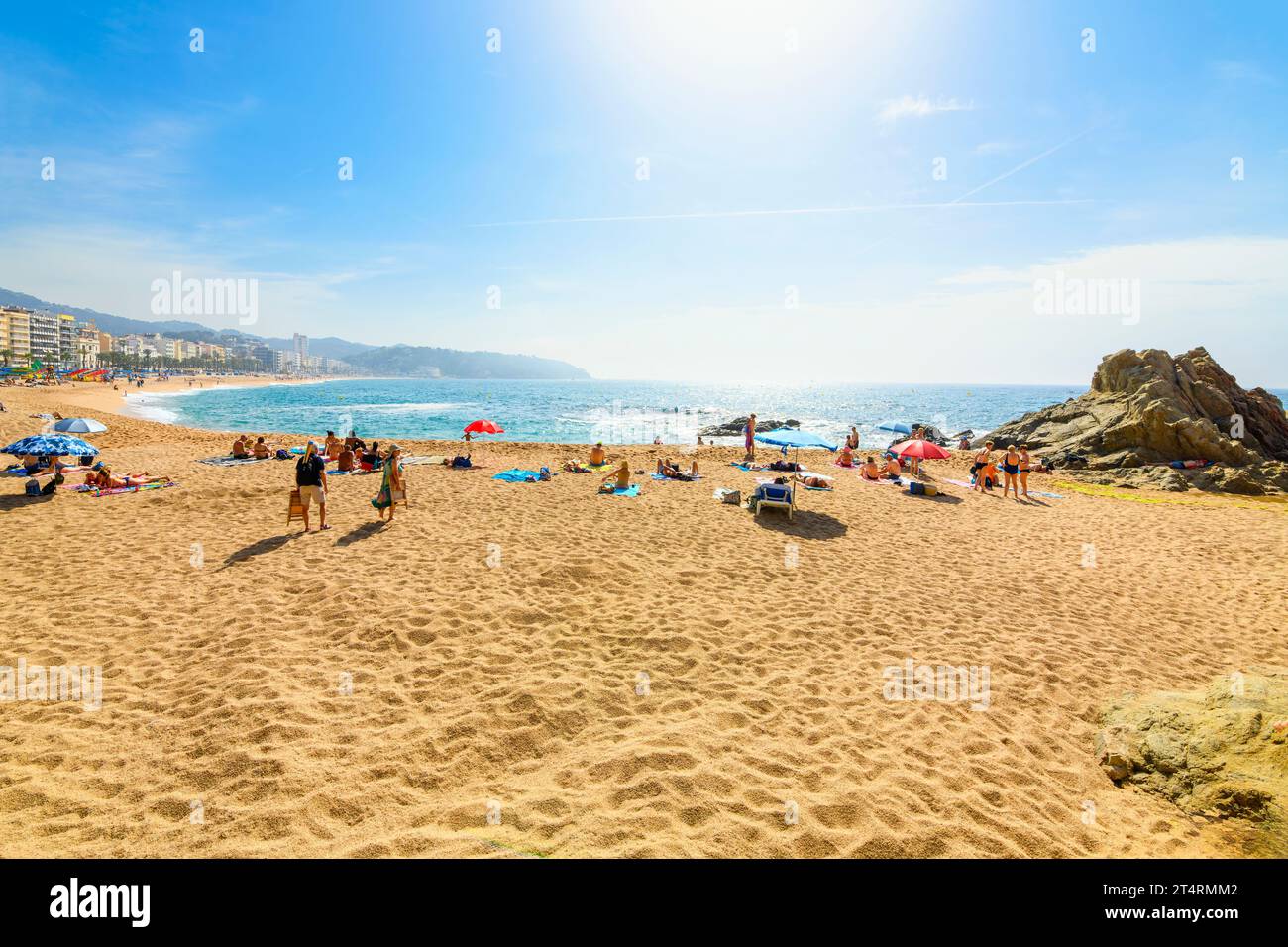 Spanier und Touristen genießen einen Sommertag am breiten Sandstrand Playa Grande im spanischen Ferienort Lloret de Mar an der Costa Brava. Stockfoto
