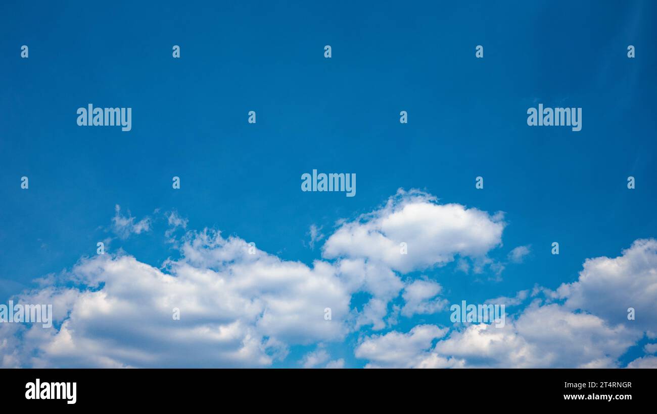 Die Leinwand des Tages ist mit einem ruhigen und ruhigen blauen Himmel bemalt, der mit flauschigen weißen Cumulus-Wolken geschmückt ist und eine friedliche Atmosphäre bietet. Stockfoto