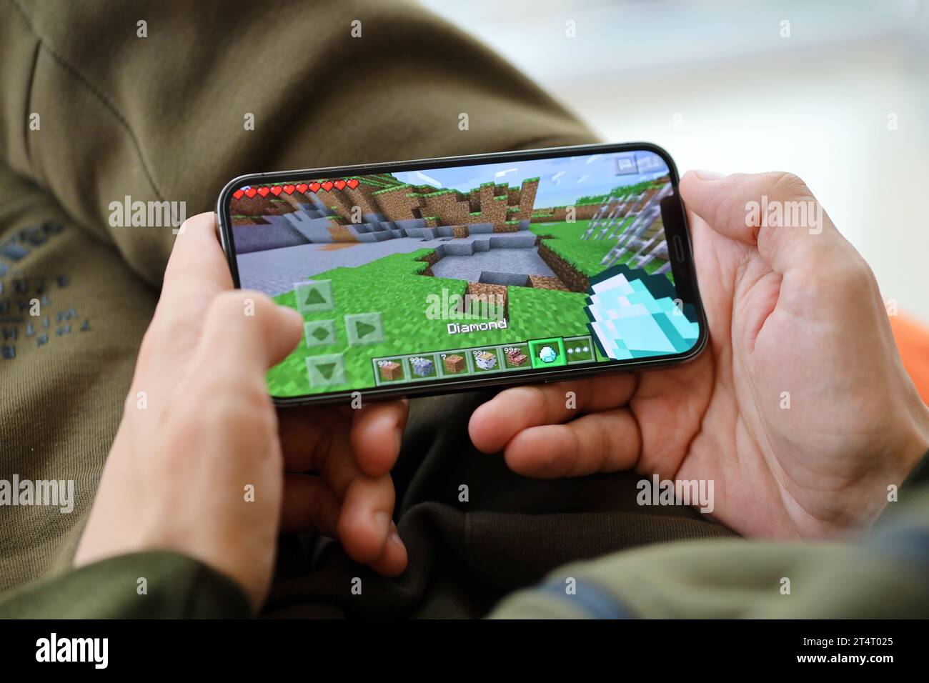 Minecraft mobiles iOS-Spiel auf dem iPhone 15 Smartphone-Bildschirm in männlichen Händen während des mobilen Gameplays. Mobiles Gaming und Entertainment auf einem tragbaren Gerät Stockfoto