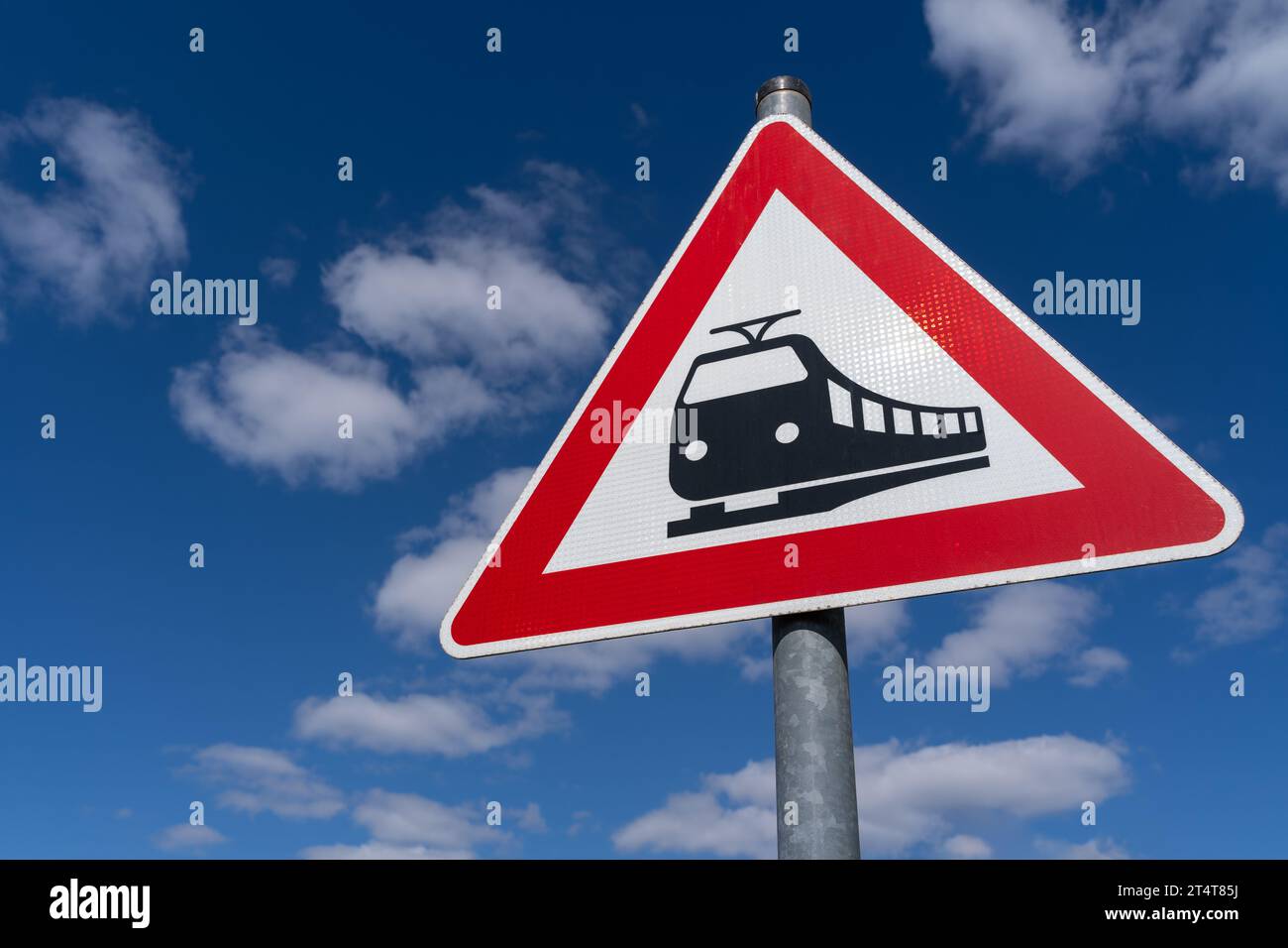 Dreieckiges Eisenbahnübergangsschild mit blauem bewölktem Himmel im Hintergrund Stockfoto