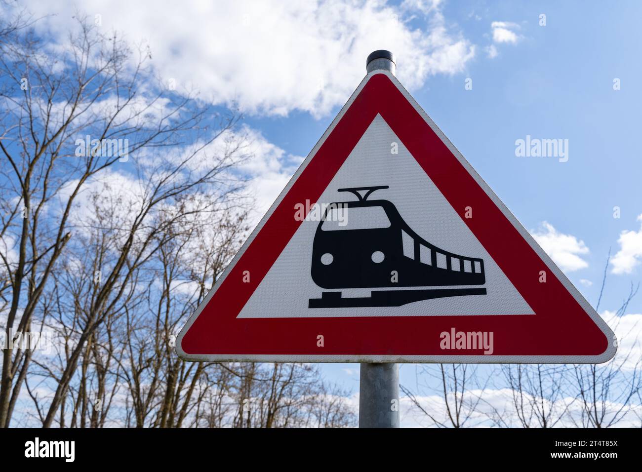 Dreieckiges Eisenbahnübergangsschild mit blauem bewölktem Himmel im Hintergrund Stockfoto