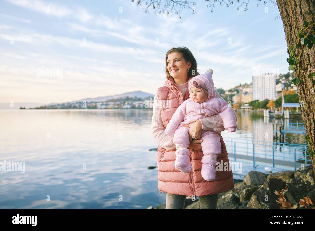 Außenporträt einer glücklichen jungen Mutter mit entzückendem Mädchen, das einen schönen Blick auf den Wintersee Genf oder Lac Leman, Montreux, Schweiz genießt Stockfoto