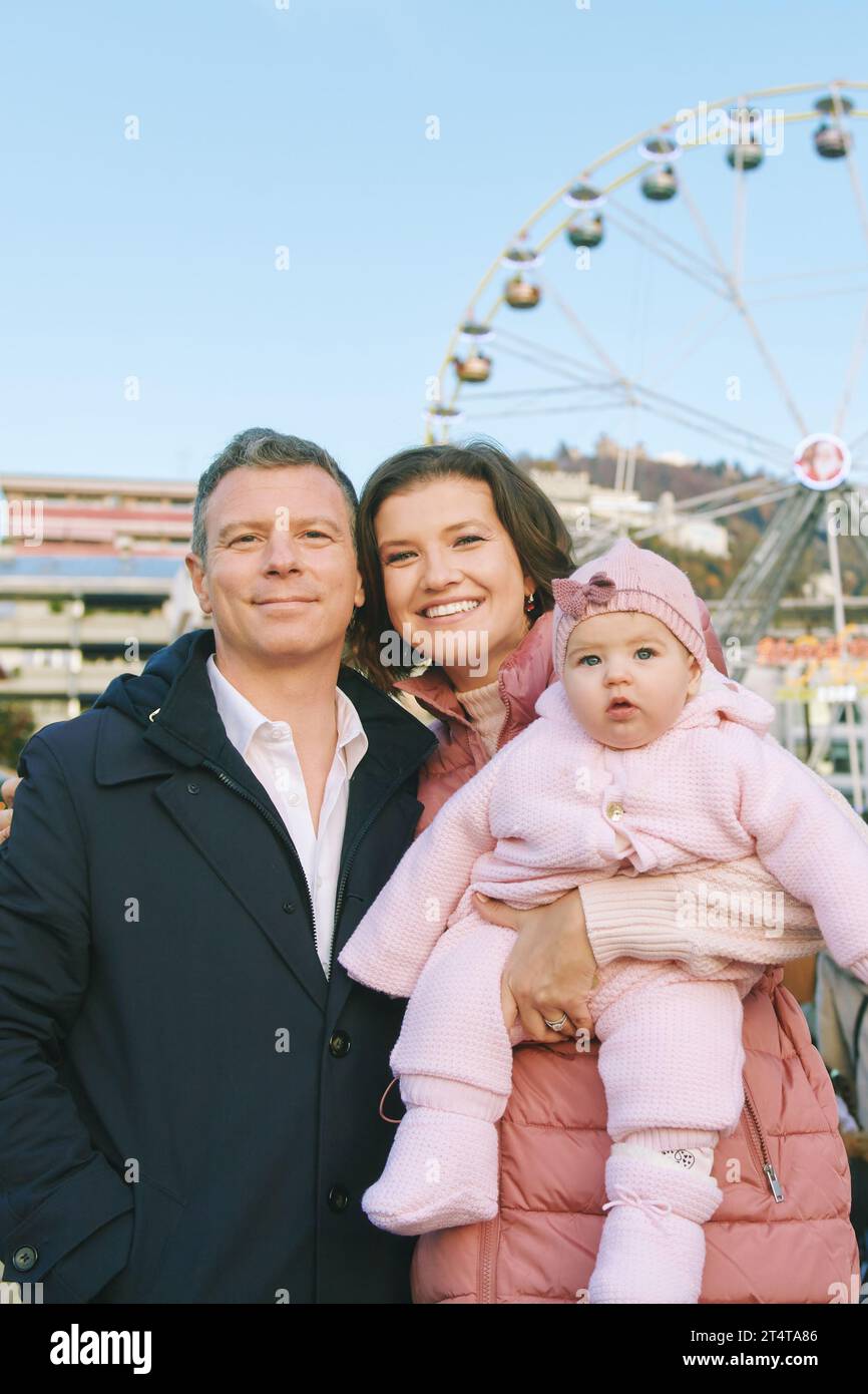 Outdoor-Porträt einer glücklichen Familie mit entzückendem Mädchen auf dem Weihnachtsmarkt Stockfoto