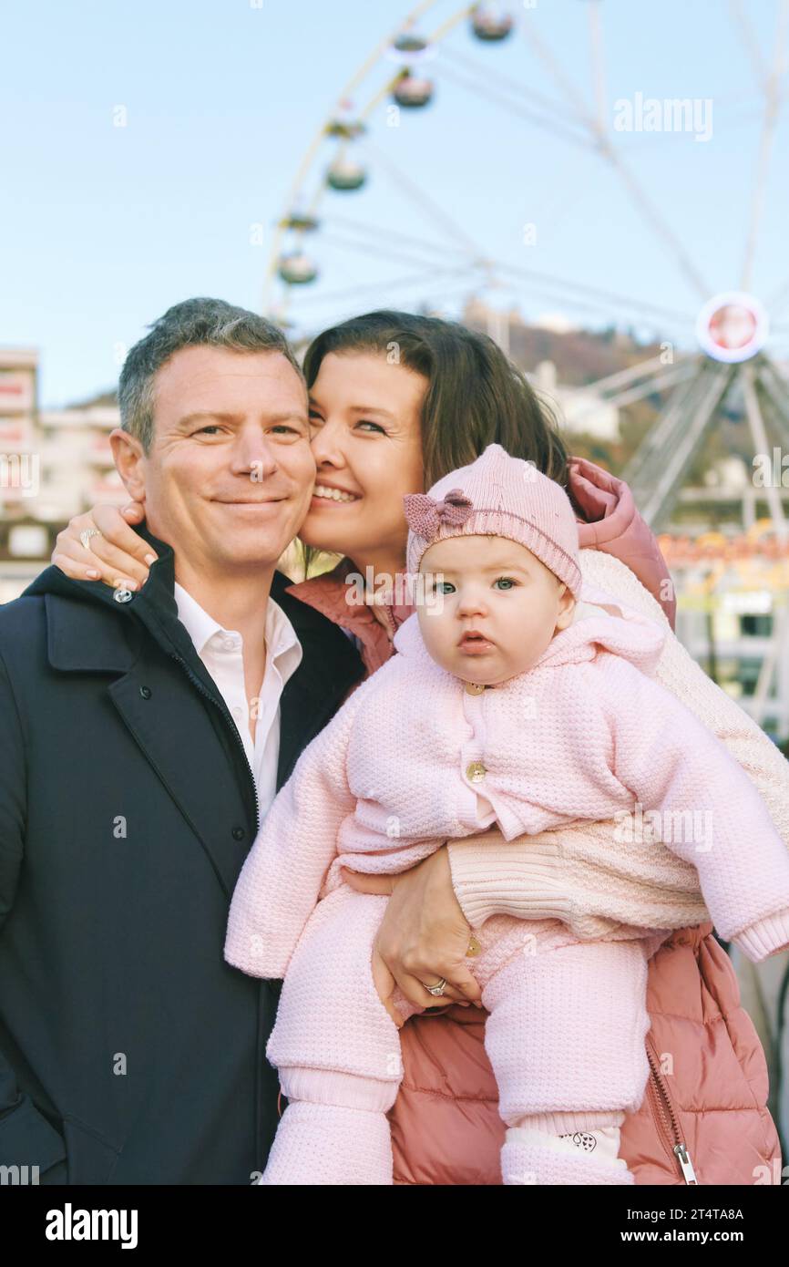 Outdoor-Porträt einer glücklichen Familie mit entzückendem Mädchen auf dem Weihnachtsmarkt Stockfoto