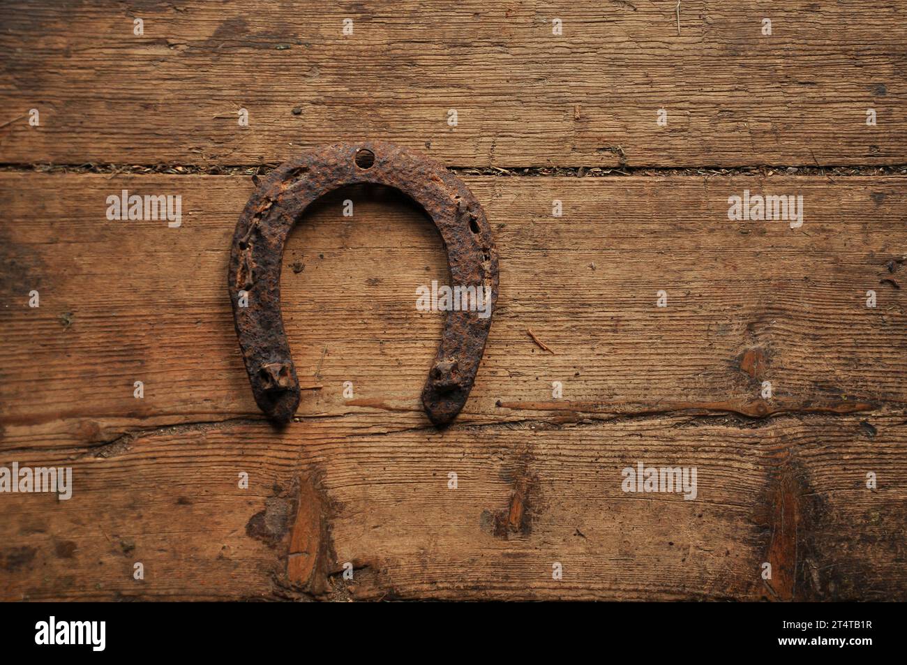 Sehr alter schäbiger Holzboden und rostiges Hufeisen. Einfacher Hintergrund. Kopierbereich Stockfoto