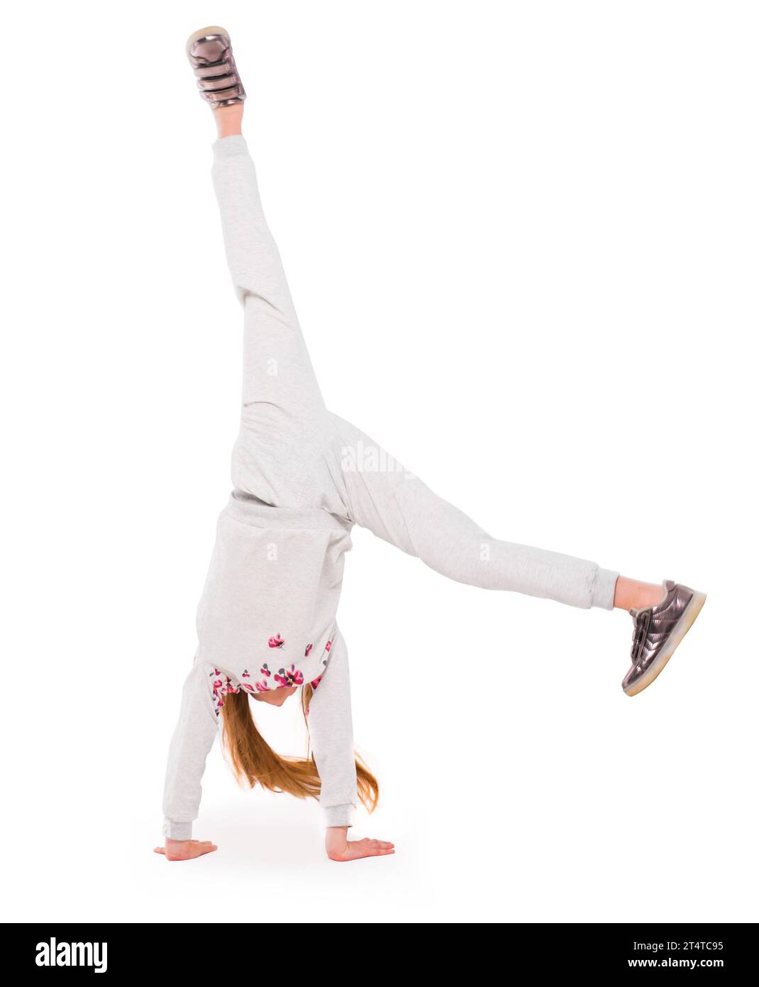 Aktives kleines Mädchen in grauen Sportkleidung dabei einen Handstand auf weißem Hintergrund Stockfoto