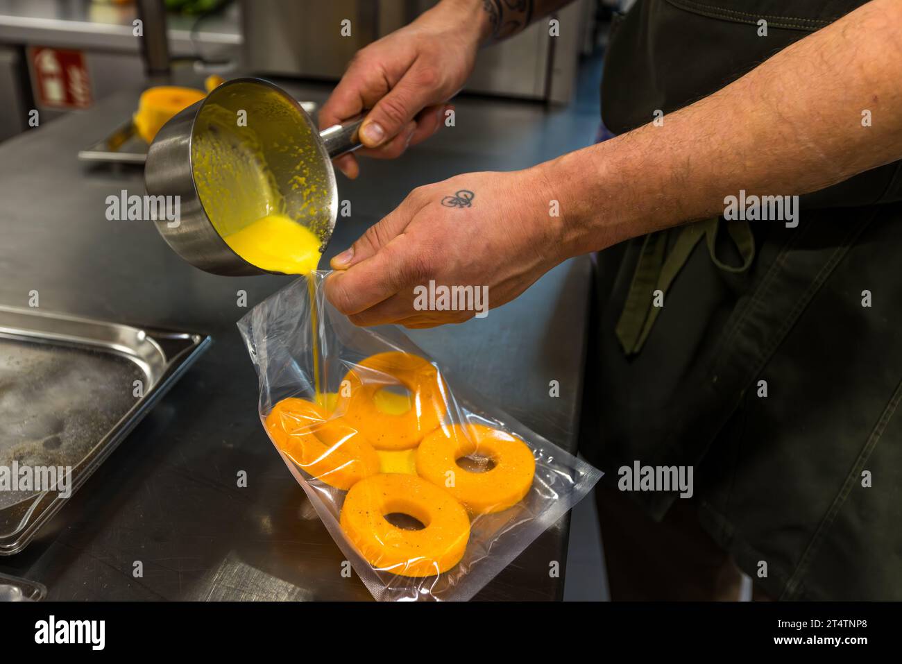 Ringe von Butternusskürbis werden sous-vide in einer Kürbisbrühe im Restaurant Holzfellas zubereitet. Chef Ingo Mark bereitet das Gericht in Wiesau, Bayern, Deutschland, zu. Stockfoto