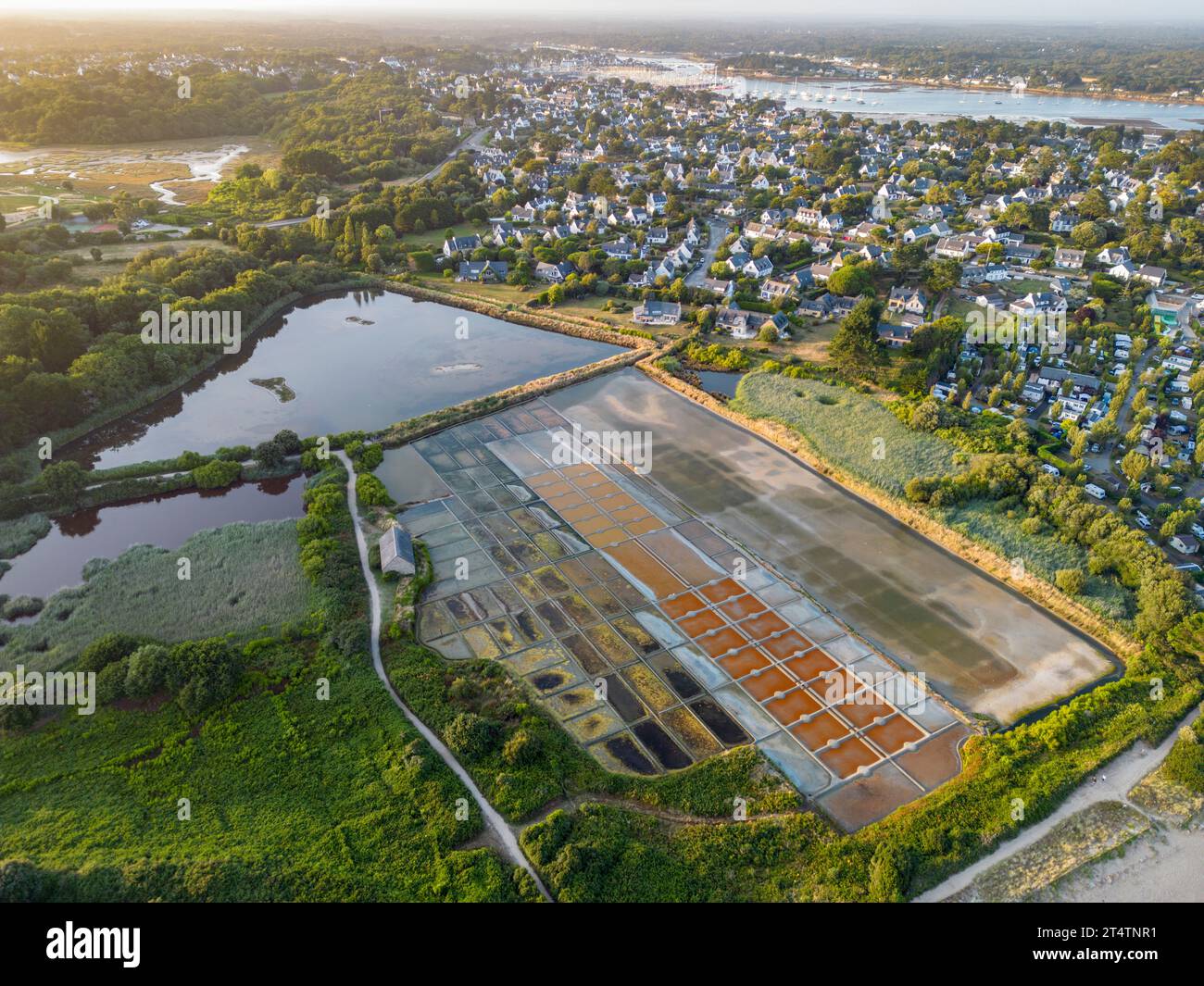 Aus der Vogelperspektive des Salzwassers Kervillen mit der Stadt La Trinité-sur-Mer im Hintergrund (Morbihan, Bretagne, Frankreich). Kleine handwerkliche Salzextraktion. Stockfoto