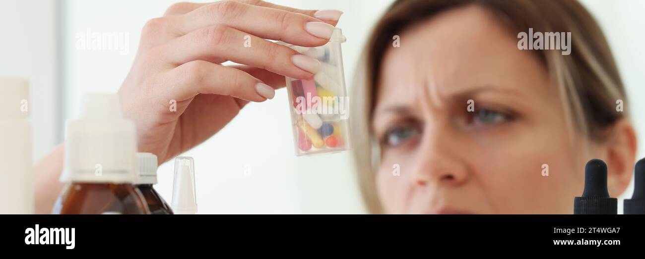 Eine Frau mit Kopfschmerzen liest Anweisungen auf der Flasche mit Pillen Stockfoto