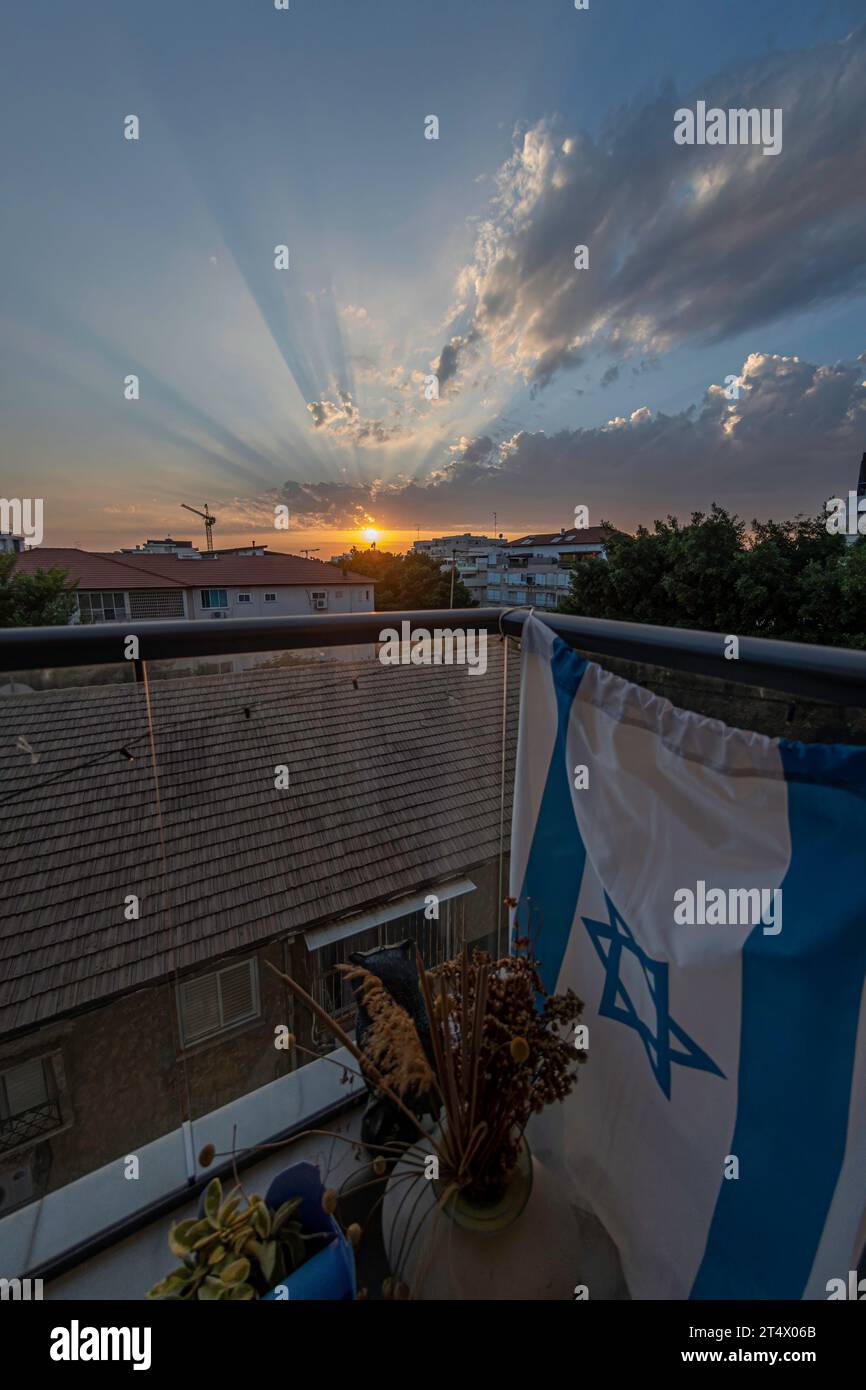 Hochauflösendes Panorama-Weitwinkelbild einer städtischen Umgebung mit einem wunderschönen Sonnenuntergang im Hintergrund mit einer israelischen Flagge Stockfoto