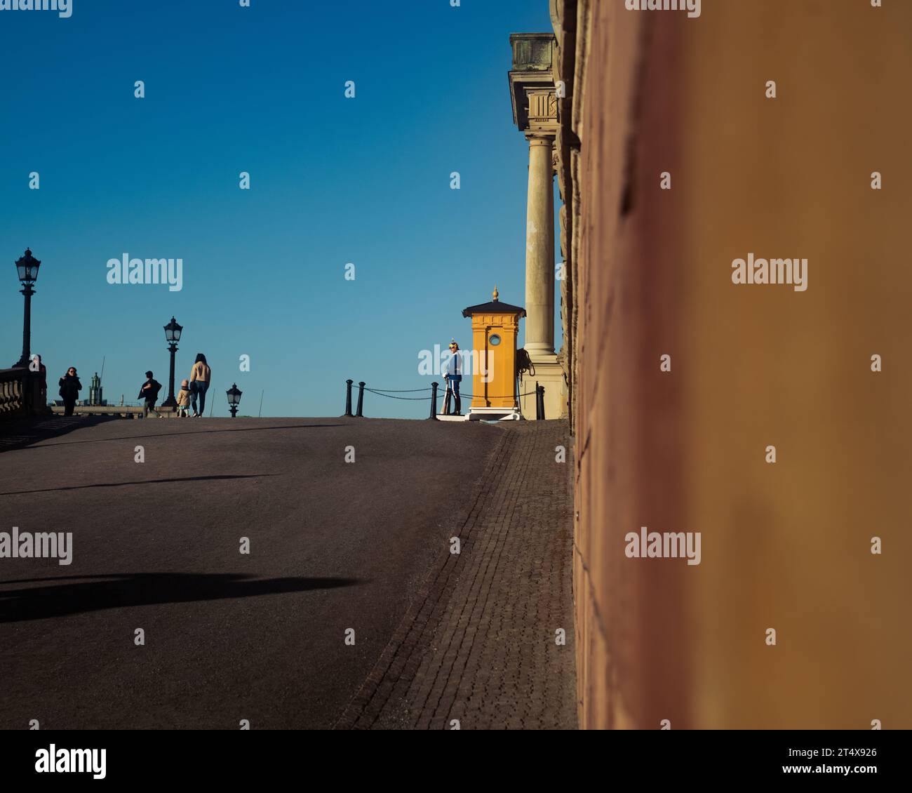 Während die Sonne über Stockholm untergeht, steht ein schwedischer Soldat Wache vor dem Königspalast, einem ergreifenden Tableau der Tradition. Stockfoto