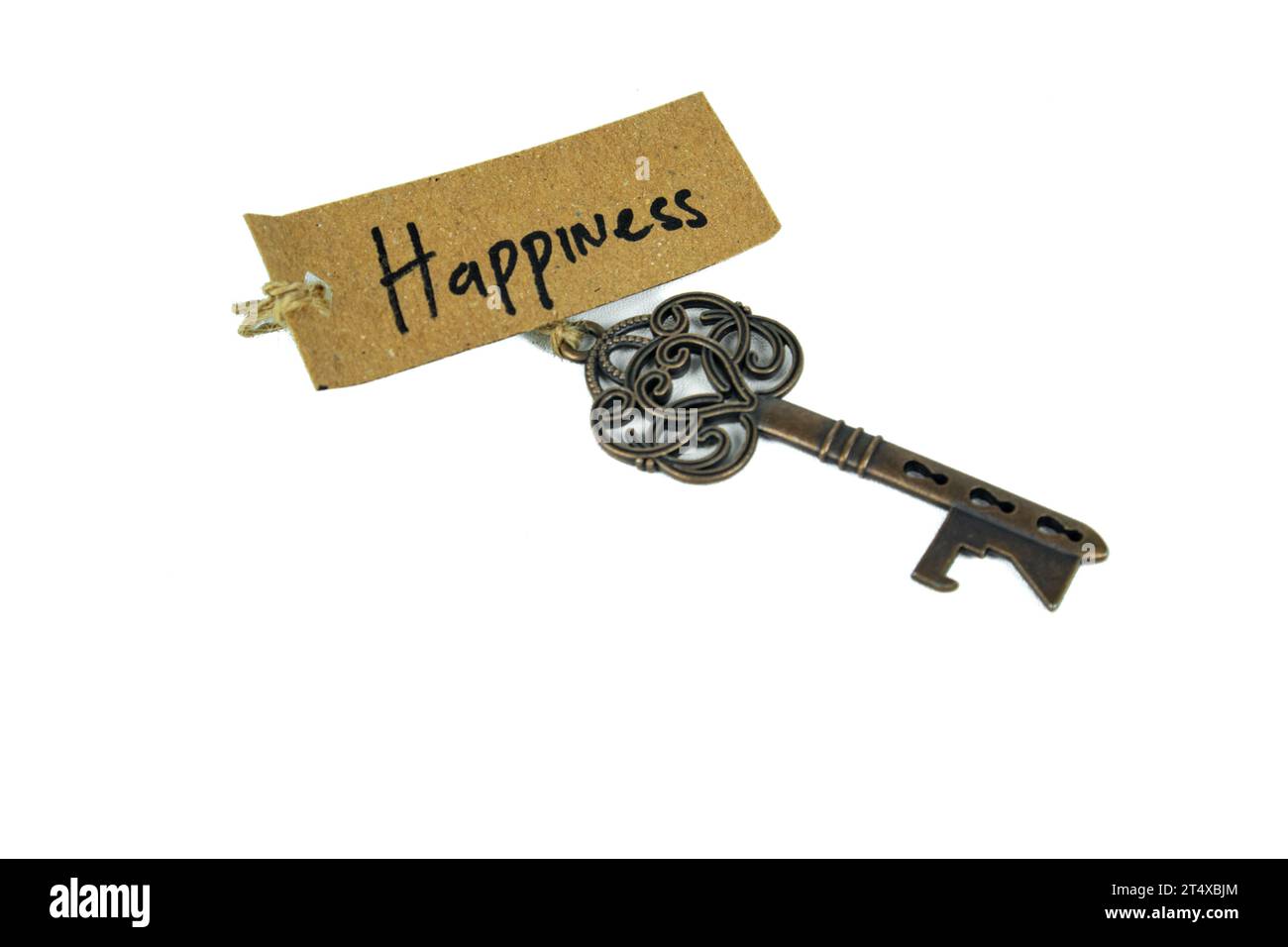 Alter dekorativer Schlüssel und handgeschriebenes Etikett „Happiness“, gebunden mit Strohseil auf weißem Hintergrund Stockfoto