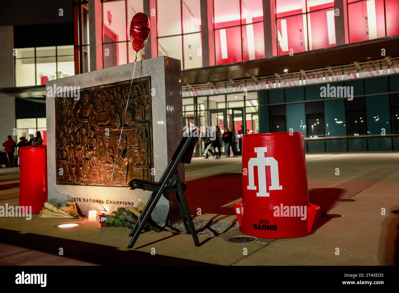 Bloomington, Usa. November 2023. Blumen und ein Stuhl befinden sich an der Basis der NCAA-Basketball-Meisterschaftstafel 1976 vor der Simon Skjodt Assembly Hall, wo Bob Knight, der verstorben ist, am 1. November 2023 in Bloomington, Indiana trainierte. Knight trainierte die Basketballmannschaft der Männer in der Assembly Hall und gewann mit seinem Team die NCAA Basketball-Meisterschaften 1976, 1981 und 1987. (Foto: Jeremy Hogan/SOPA Images/SIPA USA) Credit: SIPA USA/Alamy Live News Stockfoto