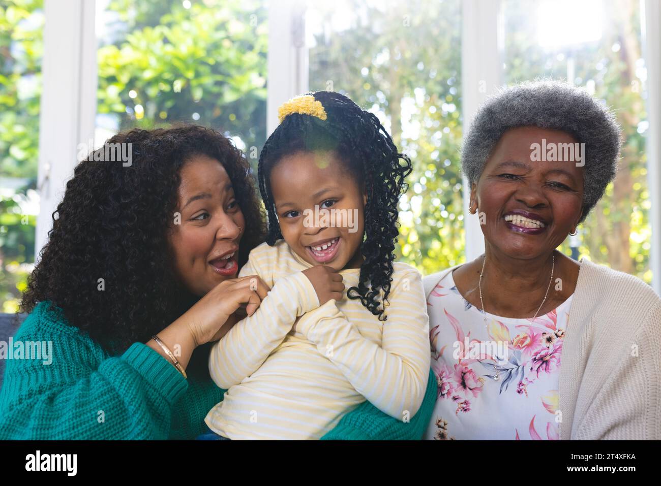 Glückliche afroamerikanische Mutter, Tochter und Enkelin, die zu Hause auf der Couch sitzen, Kopierraum Stockfoto