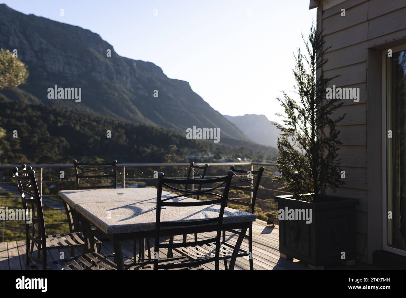 Tisch und Stühle auf der sonnigen Terrasse des Hauses mit Bergblick, Kopierraum Stockfoto