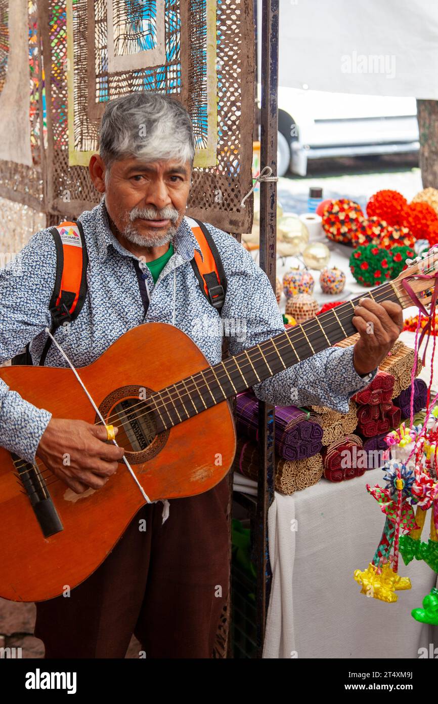 Mann spielt Gitarre für Spenden auf dem Craft Market auf der Plaza Tenanitla am San Jacinto Square und Bazar Sabado an Kunstsamstagen in Mexiko-Stadt, Mexiko Stockfoto