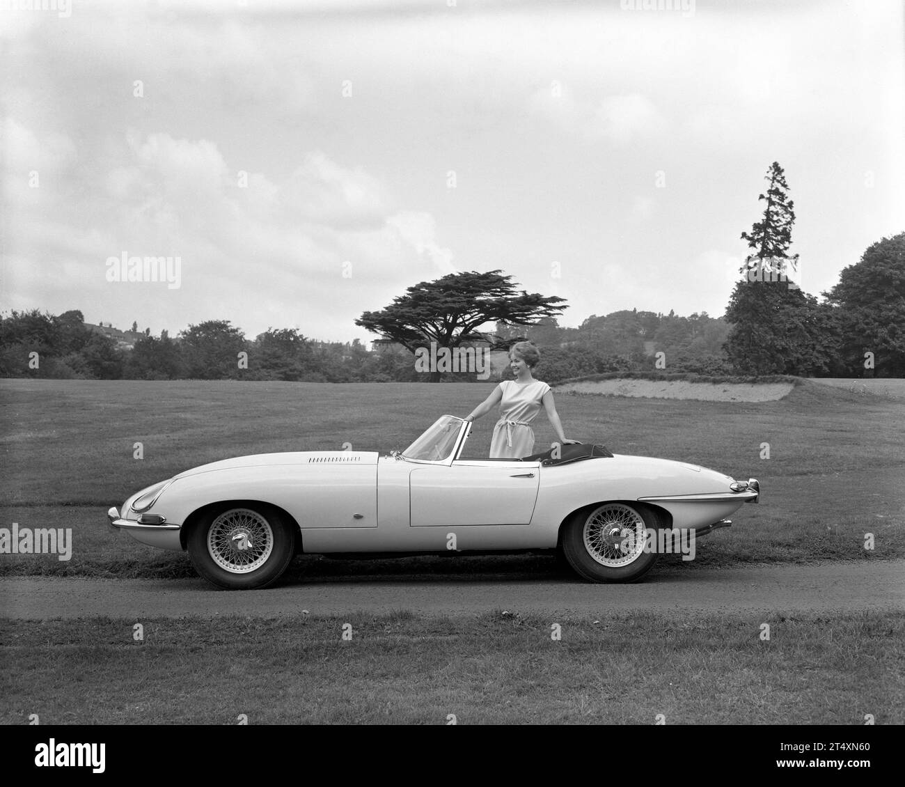 Frühe Werbefoto des Jaguar E-TYPE S1, offener Zweisitzer, 3,8 L, mit Modell in weißem Kleid. Aufgenommen im Halesowen Golf Club am 21./8/1961 Stockfoto