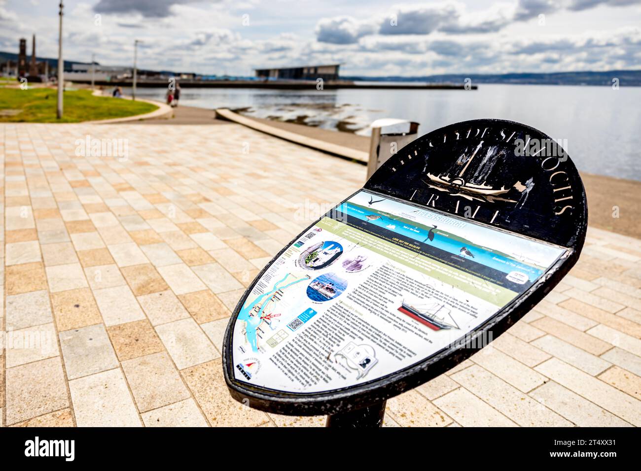 Nahaufnahme eines der Informationstafeln zum Clyde Sea Lochs Trail mit Freizeitzentrum und Pier im Hintergrund Stockfoto