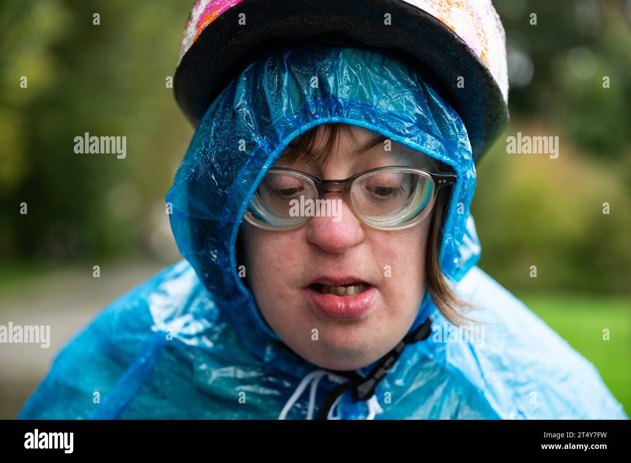 Nahaufnahme Porträt einer 41-Jährigen Frau mit Down-Syndrom, die einen Fahrradhelm und einen blauen Regenponcho trägt, Tienen, Flandern, Belgien Stockfoto