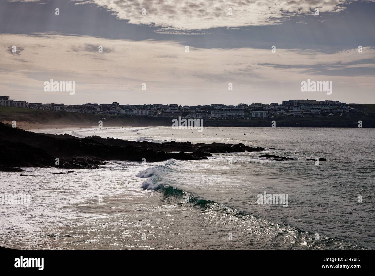 Am Little Fistral Beach, Newquay, Cornwall, brechen sonnendurchflutete Wellen auf den Felsen. Stockfoto