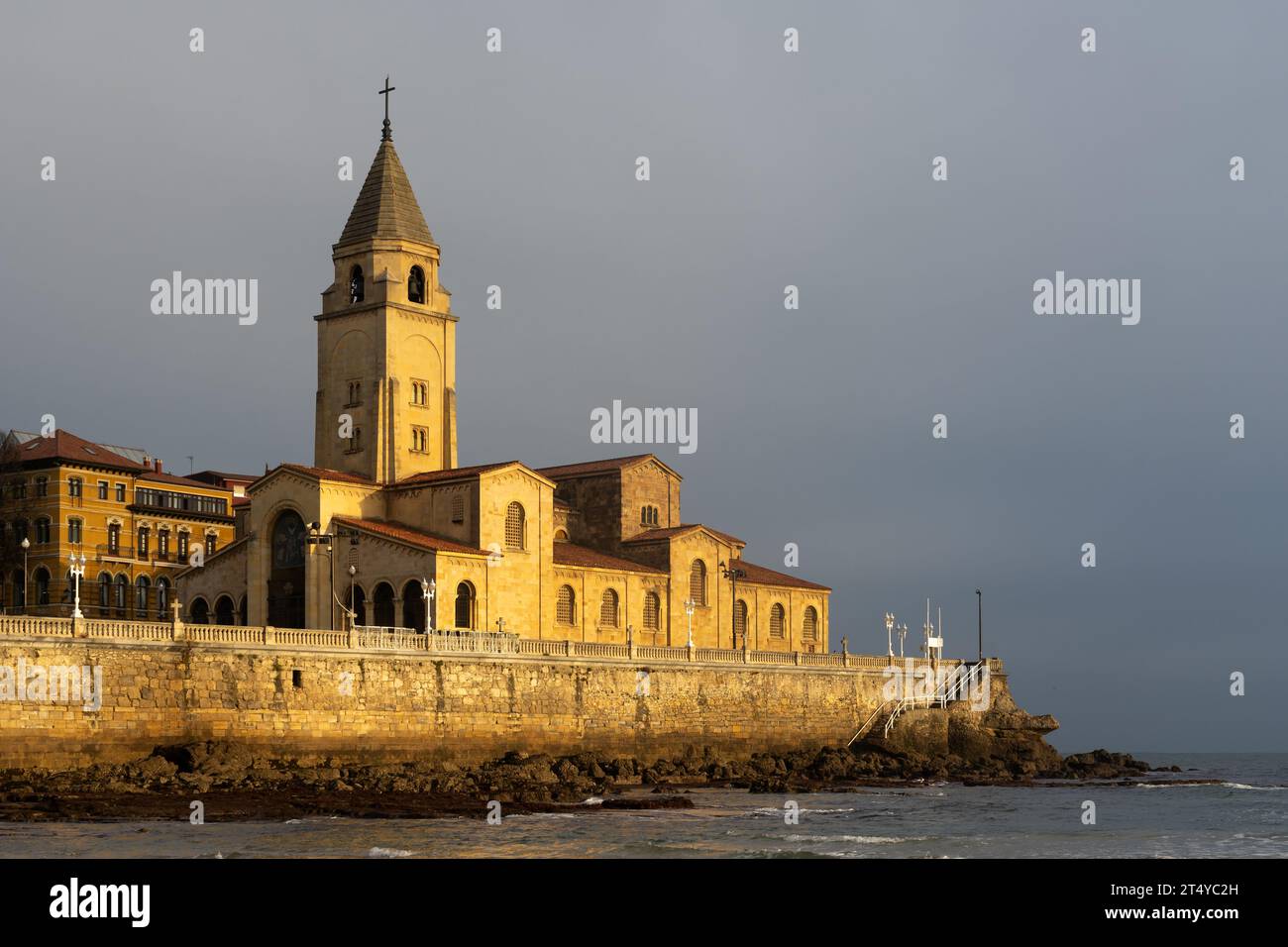 Kirche San Pedro am Strand von San Lorenzo, beleuchtet von der Sonne bei Sonnenaufgang in der Stadt Gijon, Asturien, Spanien Stockfoto