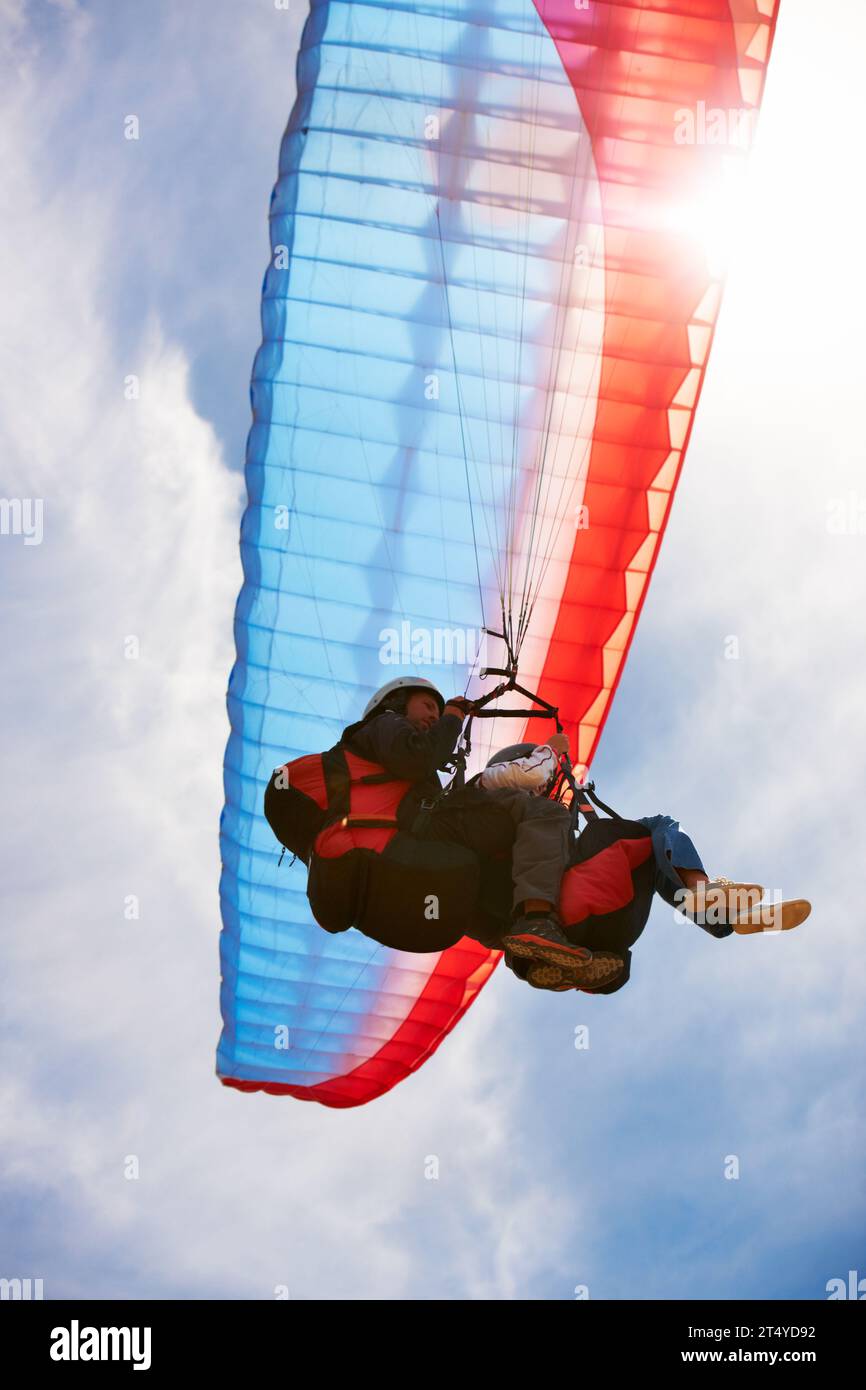 Menschen, Gleitschirmfliegen und Freiheit am Himmel, unter Wasser oder Extremsport für Fitness bei Sonnenschein. Coach, Partnerschaft und Person auf Abenteuer, Linsenflackern oder Stockfoto