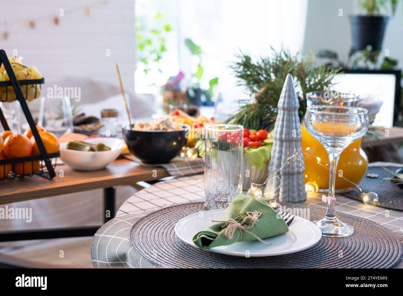 Ein festlicher Tisch mit Snacks, Salaten und Leckereien in der Nähe im modernen Innenraum eines Loft-Hauses, das zu Weihnachten und Neujahr dekoriert ist. Warten Stockfoto