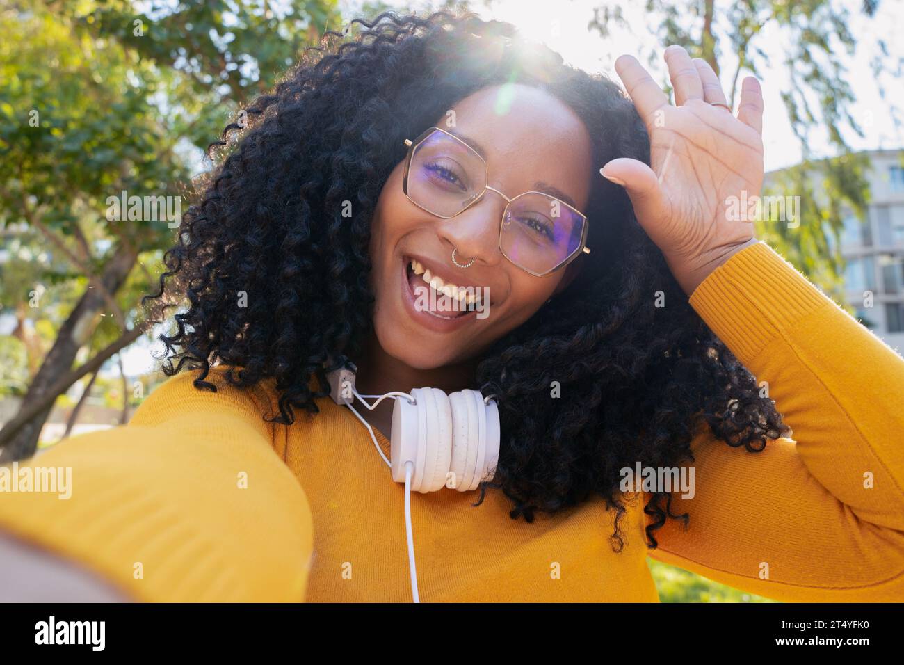 Porträt einer schönen jungen afroamerikanerin, die glücklich lächelnd in die Kamera schaut und draußen ein Selfie macht. Stockfoto
