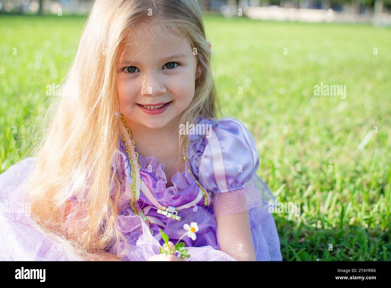 Porträt eines hübschen, lächelnden Mädchens mit langen blonden Haaren. Glückliches Kind im Freien Stockfoto