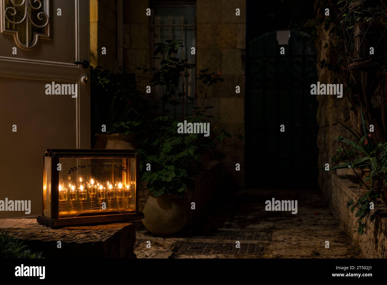 Eine Hanukkah-Menora mit der Inschrift „Eine Kerze ist eine gute Tat und die Tora ist Licht“ wird während der Feier des je vor einem Haus platziert Stockfoto