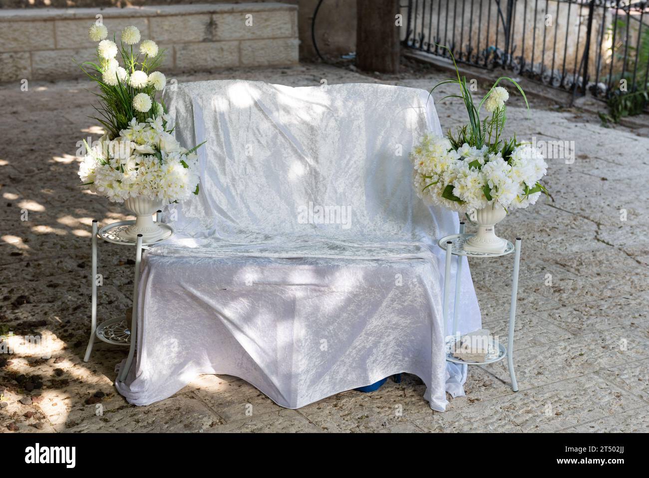 Ein dekorativer, breiter Stuhl mit Leinen und Blumen für die Braut auf einer jüdischen Hochzeit, um Freunde und Familie vor der Hochzeit zu beten und zu begrüßen Stockfoto