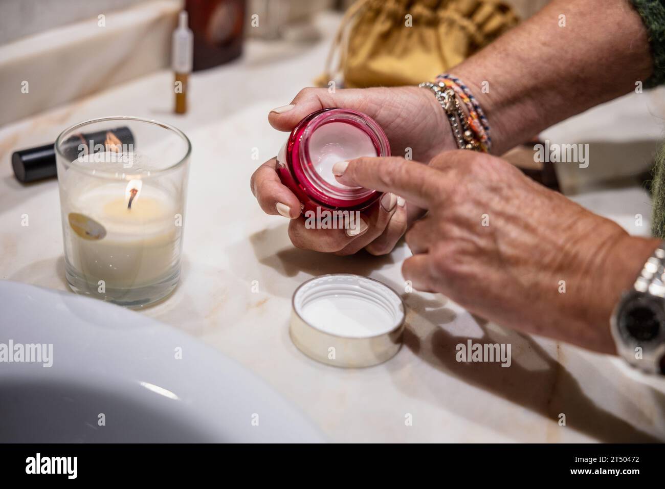 Detail der Hand der Frau, die feuchtigkeitsspendende Creme aus dem Glas nimmt, um sie aufzutragen Stockfoto