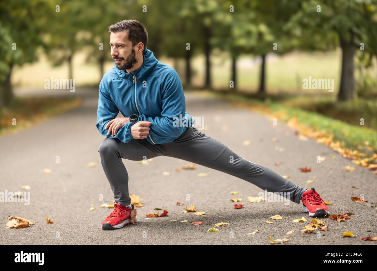 Ein junger Athlet wärmt sich vor dem Lauftraining im Park auf. Sie erwärmt den unteren Teil des Körpers. Stockfoto