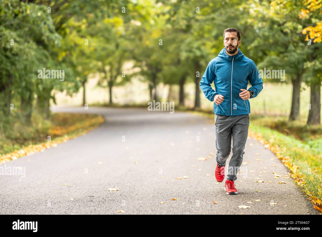 Ein junger Mann trainiert und läuft in einem Herbstpark. Stockfoto