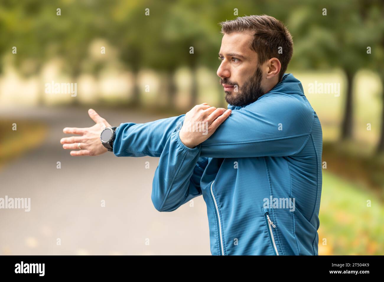 Ein junger Athlet wärmt sich vor dem Lauftraining im Park auf. Sie erwärmt den oberen Teil des Körpers. Stockfoto