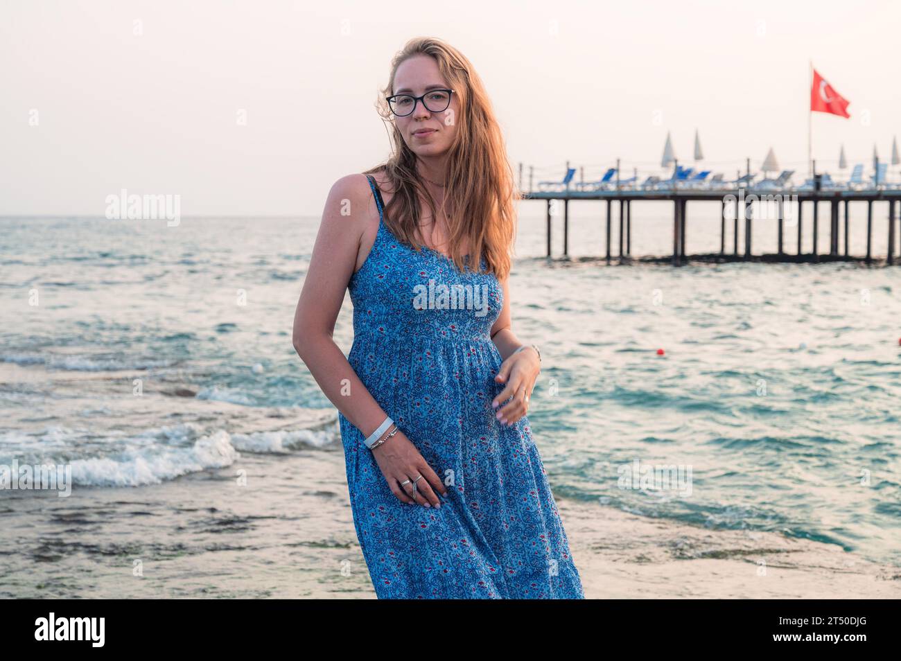 Frau sitzt am Strand und schaut auf das Meer in Alanya, Türkei. Reise- oder Urlaubskonzept Stockfoto