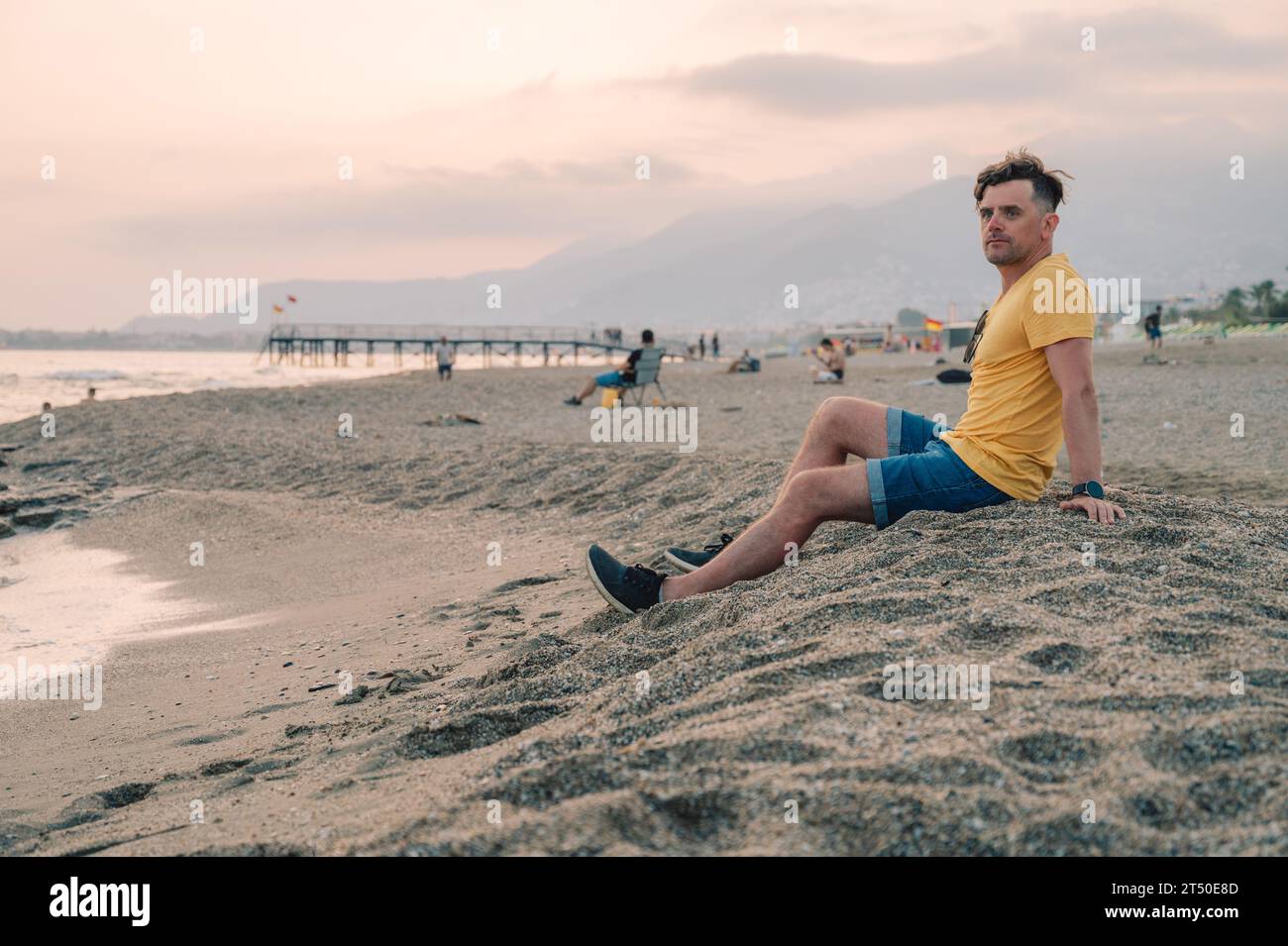 Der Mann sitzt am Strand und blickt auf das Meer in Alanya City, Türkei. Reise- oder Urlaubskonzept Stockfoto