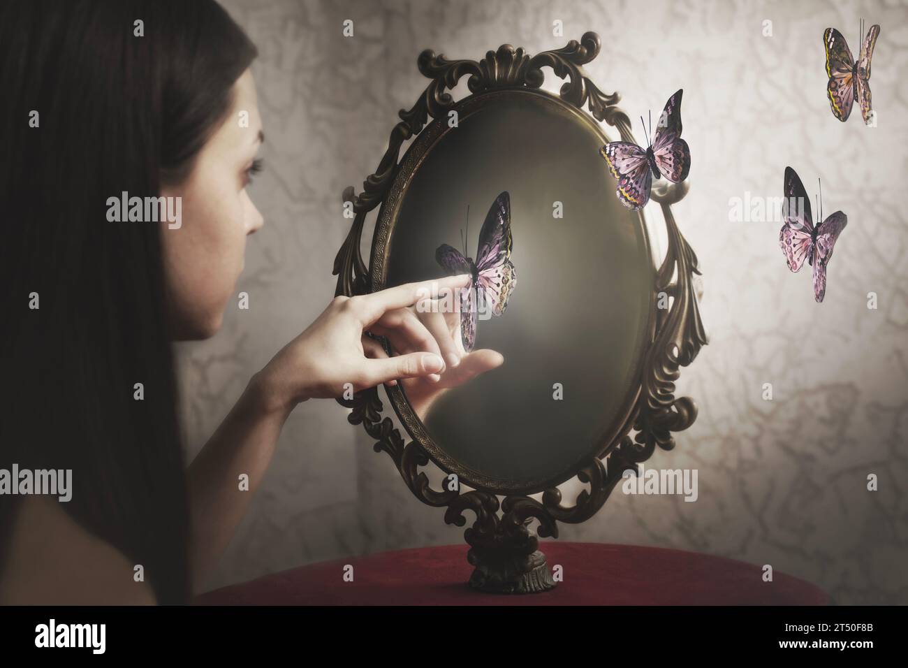 Frau überrascht von ihrem Ausstieg aus dem Spiegel surrealer Schmetterlinge; ; Konzept der Selbstbetrachtung und Freiheit Stockfoto