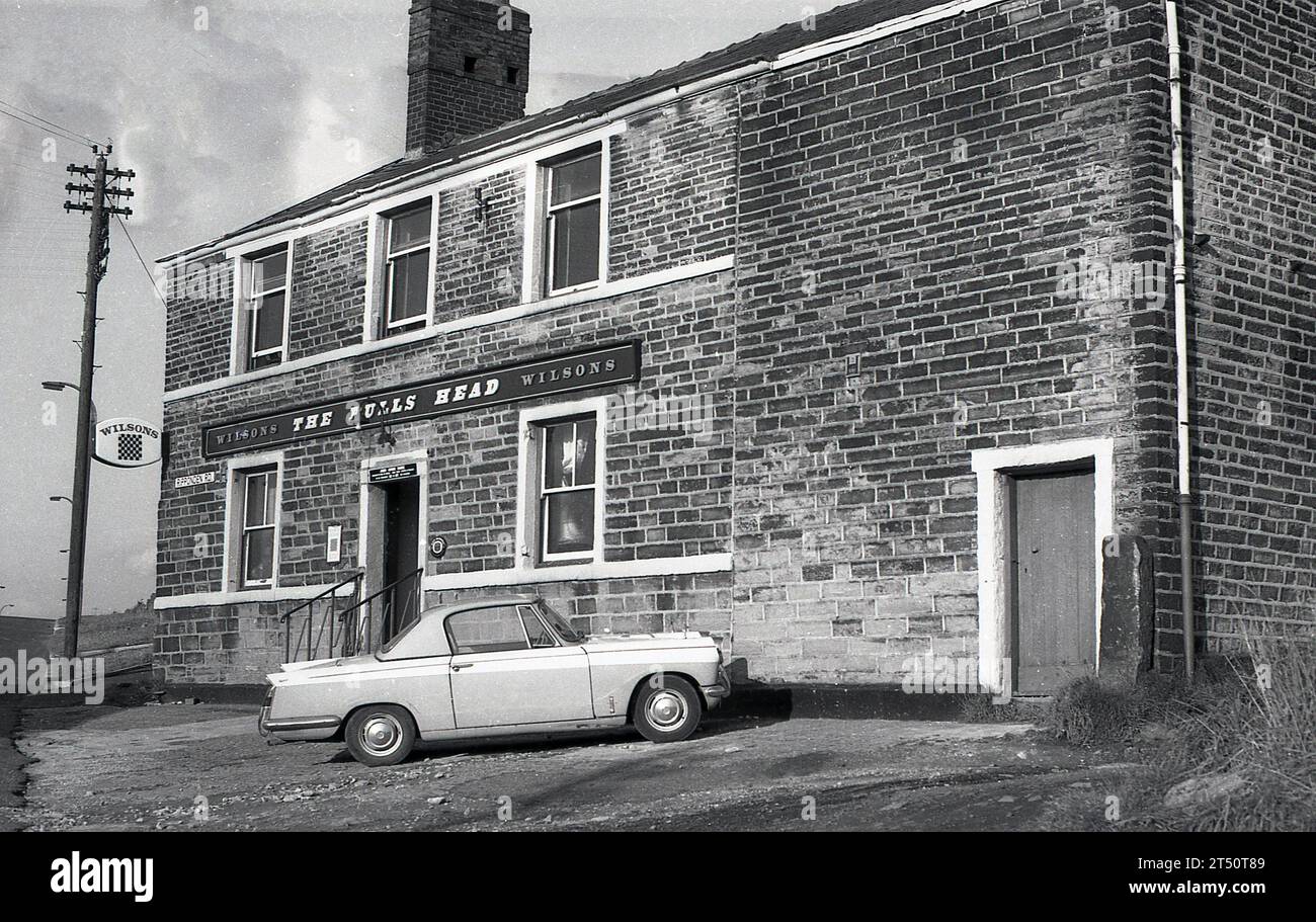 1960er Jahre, ein historischer Wagen von Triumph Herald, der vor dem Bulls Head, einem Pub der Wilson's Brewery, an der Ripponden Rd, Oldham, England, Großbritannien, geparkt wurde. Sie wurde 2015 geschlossen. Stockfoto