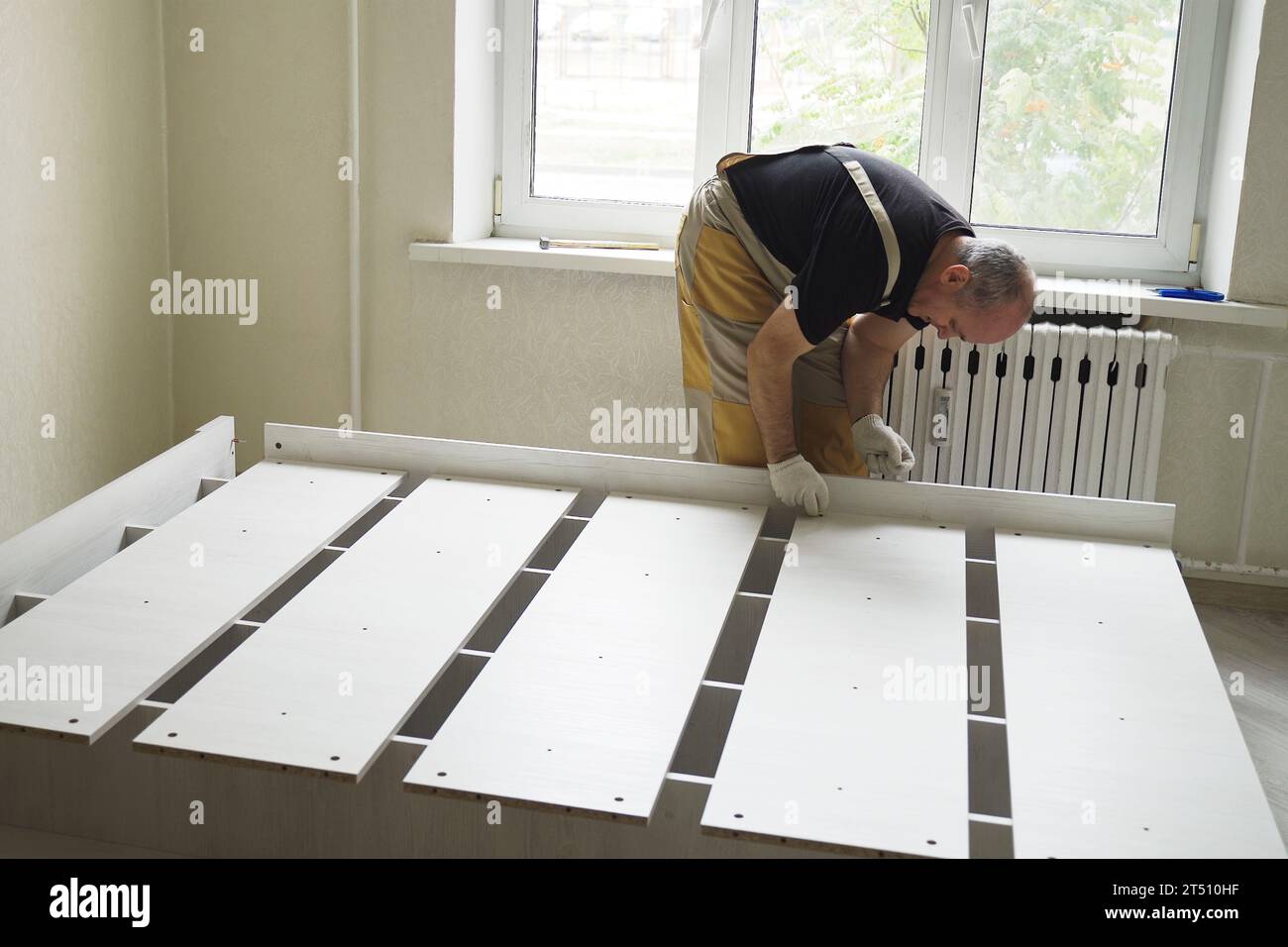 Ein Arbeiter baut Möbel zusammen und verbindet die Teile des Bettes. Möbelmontage. Zeitraffer, beschleunigtes Video. Stockfoto