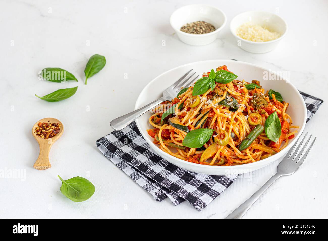 Pasta Pomodoro garniert mit frischen Basilikumblättern, Kräutern und Käse in einer Schüssel auf weißem Hintergrund Stockfoto