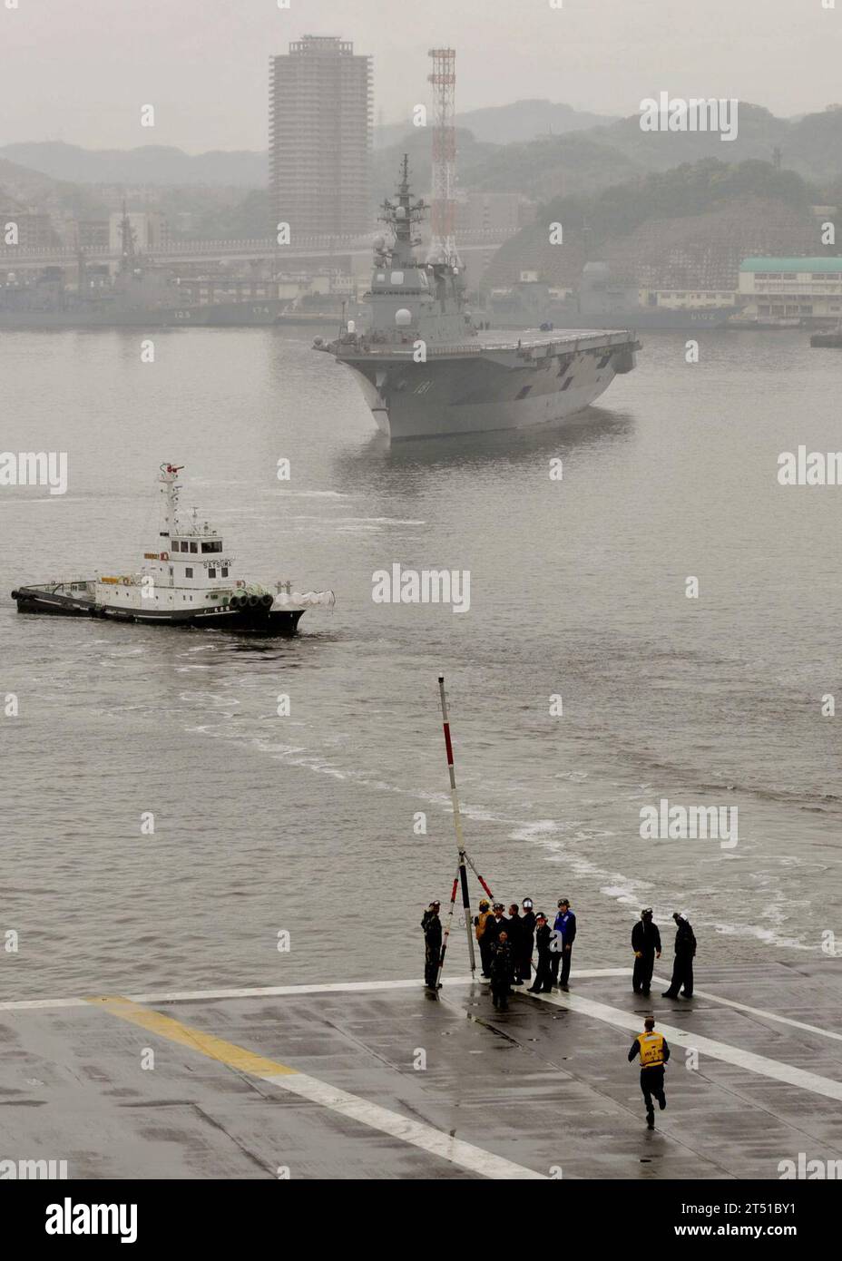 1005114830B-017 YOKOSUKA, Japan (11. Mai 2010) Seeleute zerlegen die flagstaff an Bord des Flugzeugträgers USS George Washington (CVN 73), nachdem sie die Yokosuka Naval Base verlassen haben, während der Hubschrauber-Zerstörer JS Hyuga (DDH 181) im Hintergrund unterwegs ist. George Washington führt Seeversuche im westlichen Pazifik durch, nachdem eine selektive eingeschränkte Verfügbarkeit abgeschlossen wurde. Marineblau Stockfoto