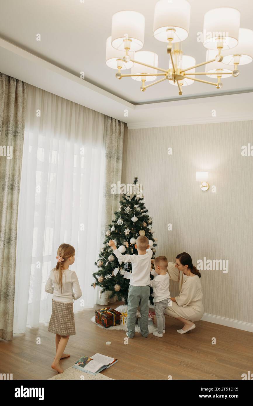 Kinder hängen Wünsche an den Weihnachtsbaum. Familientraditionen. Stockfoto