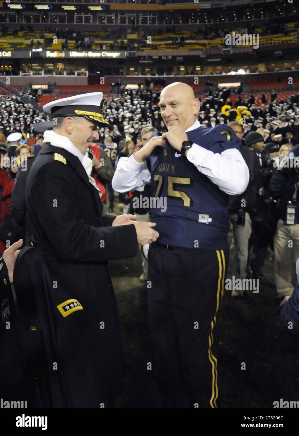 111210FC670-050 LANDOVER (10. Dezember 2011) Chief of Naval Operations (CNO) ADM. Jonathan Greenert, links, unterstützt den Stabschef des Army General Raymond T. Odierno beim Anziehen eines Navy Football Trikots, nachdem die U.S. Naval Academy Midshipmen die U.S. Military Academy Black Knights 27-21 besiegt hatten. Marineblau Stockfoto