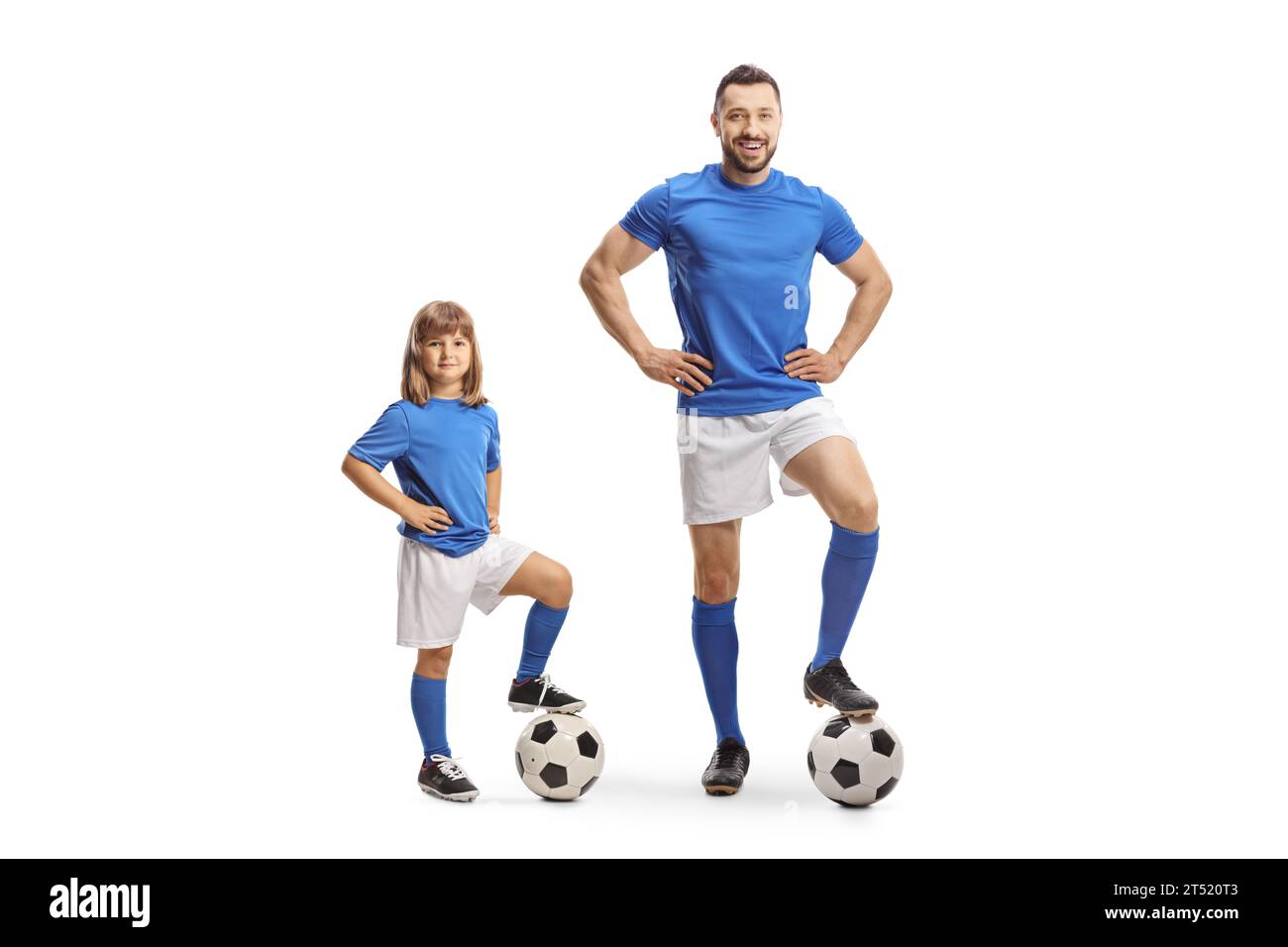 Mädchen im Sporttrikot, das mit Fuß auf einem Fußball neben einem Fußballspieler auf weißem Hintergrund steht Stockfoto