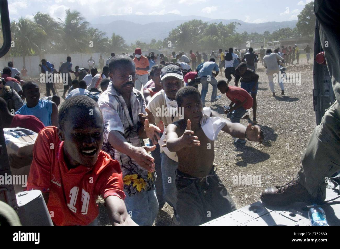 1001166006S-063 PORT-AU-PRINCE (16. Januar 2010) Haitianische Staatsbürger erhalten Wasser von Flugzeugbesatzungen der Helicopter Sea Combat Squadron (HSC) 9, die dem Flugzeugträger USS Carl Vinson (CVN 70) zugeordnet ist. Carl Vinson und Carrier Air Wing (CVW) 17 führen humanitäre und Katastrophenhilfe durch, nachdem ein Erdbeben der Stärke 7,0 schwere Schäden in der Nähe von Port-au-Prince am 12. Januar 2010 angerichtet hatte. Marineblau Stockfoto