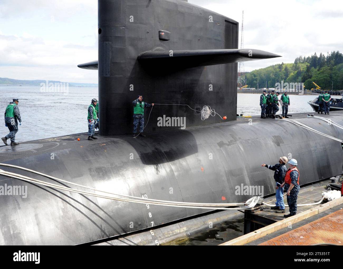 1005061325N-003 BANGOR, Washington (6. Mai 2010) Ein Matrose, der dem U-Boot USS Nevada (SSBN 733) zugewiesen ist, wirft einen Affenball an Mitglieder der Liegebesatzung, die der Naval Intermediate Maintenance Facility Pacific Northwest zugewiesen ist, während das U-Boot auf der Marinebasis Kitsap ankommt. Nevada kehrt nach einer zweijährigen Umrüstung und Betankung auf der Puget Sound Naval Shipyard in Bremerton, Washington (U.S. Navy) zurück Stockfoto