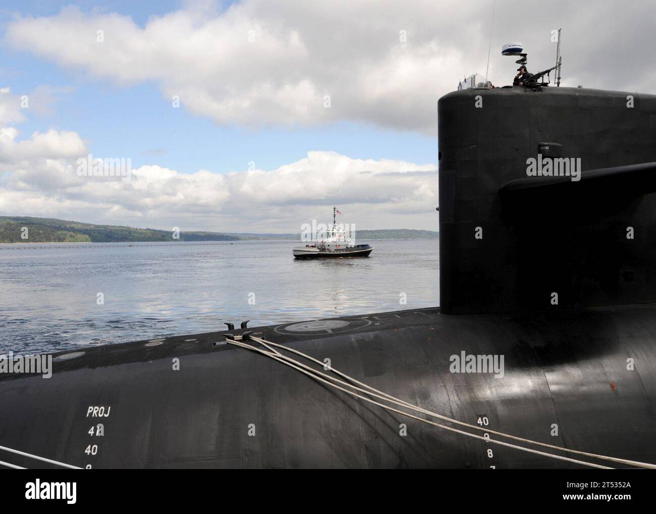 1005061325N-004 BANGOR, Washington (6. Mai 2010) Ein Schlepper fährt mit dem ballistischen Raketen-U-Boot USS Nevada (SSBN 733), als Mitglied der Besatzung im submarineХs Segel auf der Marinebasis Kitsap wacht. Nevada kehrt nach einer zweijährigen Umrüstung und Betankung auf der Puget Sound Naval Shipyard in Bremerton, Washington (U.S. Navy) zurück Stockfoto