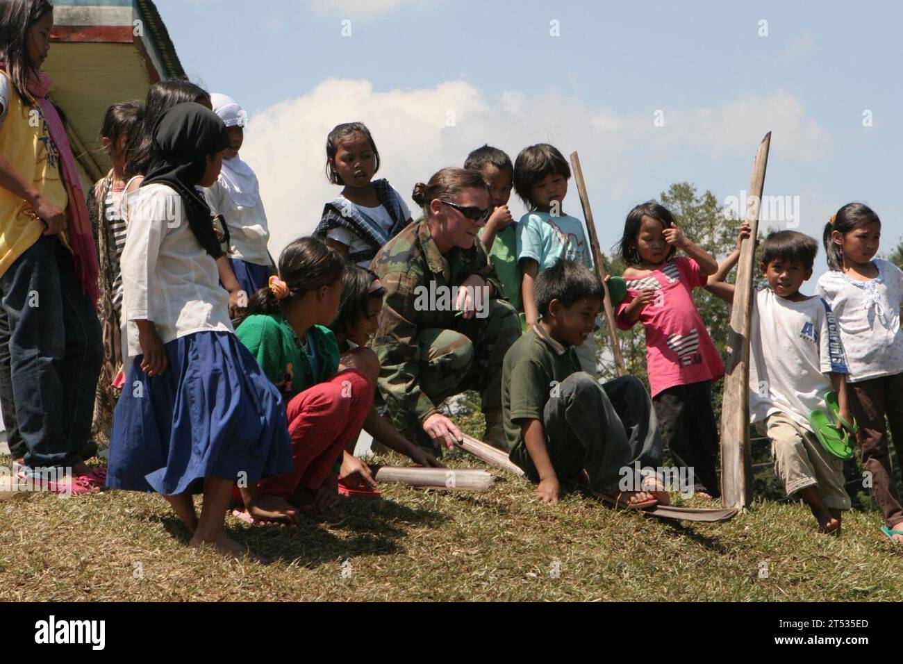 1003016309C-018 LANAO DEL SUR, Philippinen (1. März 2010) Ein Seabee, der der Joint Special Operations Task Force-Philippines zugewiesen ist, spielt mit Kindern bei einer Zeremonie für zwei Schulgebäude am Lanao Agricultural College in Barangay Lumbatan in der Gemeinde Lanao Del Sur. Seabees, die der Task Force zugeteilt wurden, arbeiteten mit lokalen Beamten, Auftragnehmern und den Streitkräften der Philippinen zusammen, um den offiziellen Wechsel der Klassenzimmer an College-Administratoren zu feiern. (U.S. Marine Corps Stockfoto