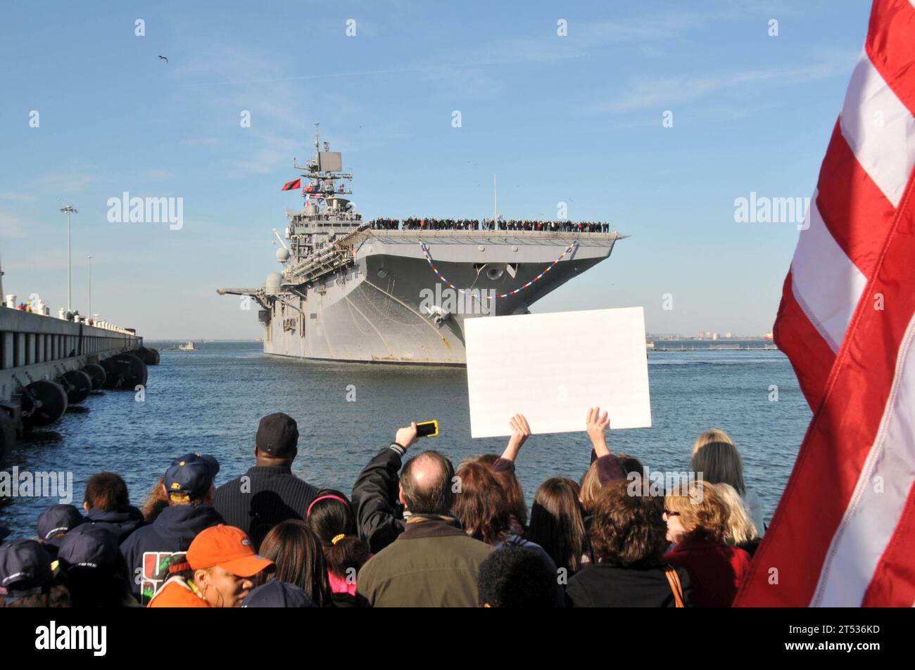 120207QY430-064 NORFOLK (7. Februar 2012) Eine Menge jubelt, als das amphibische Angriffsschiff USS Bataan (LHD 5) nach einem 10 1/2 monatigen Einsatz in den Zuständigkeitsbereichen der 5. Und 6. Flotte in die Marinestation Norfolk einreist. Die Homecoming markiert das Ende des längsten Einsatzes für ein Schiff der US Navy seit mehr als vierzig Jahren. Bataans amphibische Bereitschaftsgruppe unterstützte die Operationen Enduring Freedom, Odyssey Dawn und die NATO-geführte Operation Unified Protector und führte maritime Sicherheitsoperationen im Mittelmeer und im Arabischen Meer durch. Stockfoto